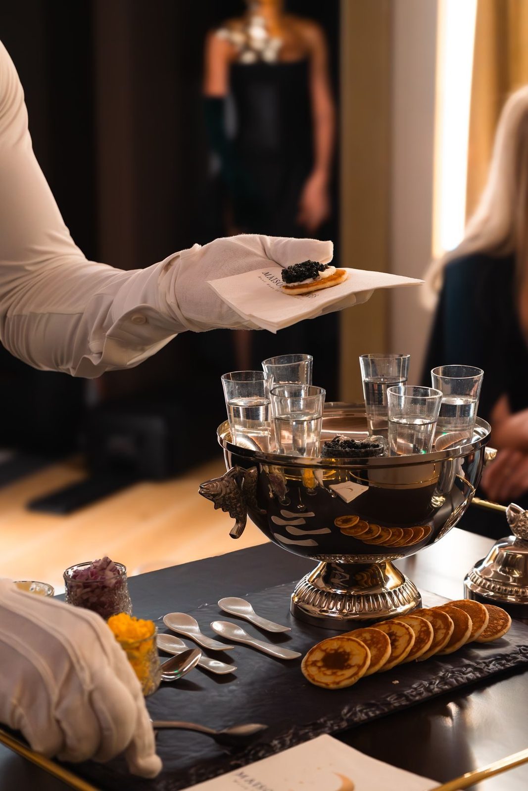 Gloved caviar service from a silver bowl